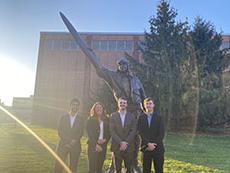 Team members posted outside in front of a pilot statue