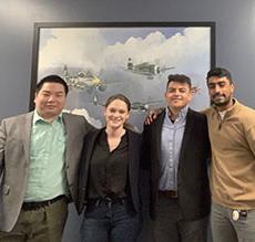 Team posed for a group shot in front of a picture of planes